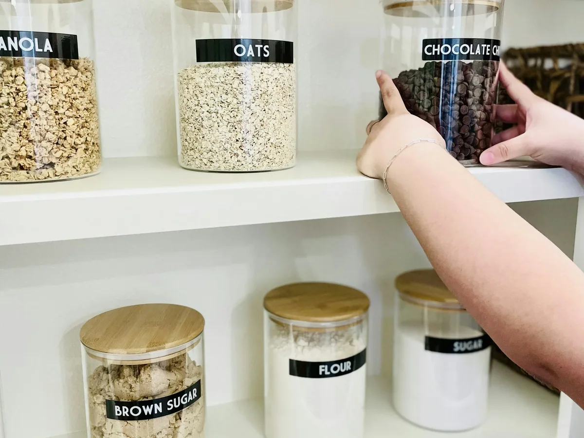 Roll-out pantry tray with full-extension glides holding dry goods and small appliances